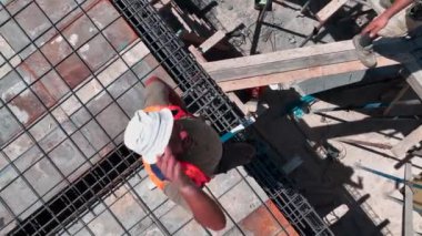 İnşaat alanında güçlendirilmiş bir temel oluşturmak için inşaat demirini bağlayan işçileri izleyin.