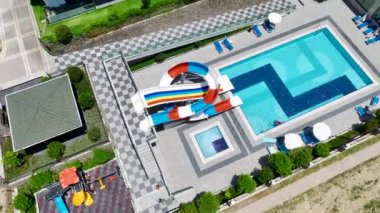 Berrak mavi suyu olan, yemyeşil palmiye ağaçlarıyla çevrili güzel bir gök mavisi havuzu izleyin..