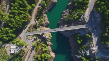 Bir modelin nehir boyunca üstü açık bir araçla güzel bir köprüden geçişini izle..