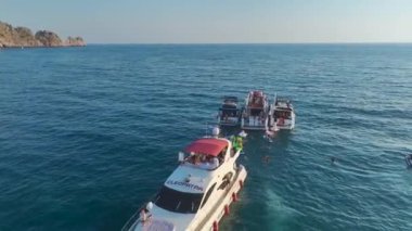 DJ 'i çalarken ve kızlar beyaz yatlarda dans ederken izleyin. Güzel gök mavisi sahil şeridinde demirli..