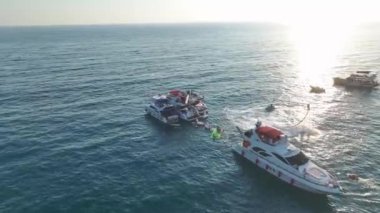 Gök mavisi kıyı şeridinde beyaz yatlarda dans eden kızların olduğu heyecan verici DJ partisine bakın..