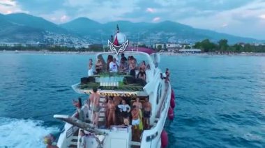 Gök mavisi sahil boyunca beyaz yatlarda DJ 'lere dans eden kızları seyredin..