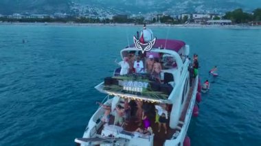 Gök mavisi kıyısı boyunca beyaz yatlarda dans eden DJ ve kızlarla parti sahnesini izleyin..
