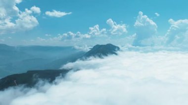 Bereketli yeşil ormanları ve geniş açık alanları olan bulutlu bir dağ manzarasının tadını çıkar..