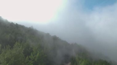 Gökyüzünü yeşil ormanlar ve bulutlarla dolduran büyülü dağ manzarasını izleyin..