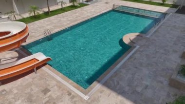 Su kaydırağıyla ferahlatıcı bir havuz. Aileler için mükemmel. Güneşli bir günün tadını çıkarıyorlar..