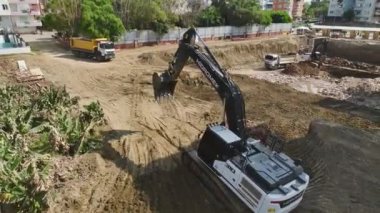 Kazı makineleri ve kamyonlarla 4K 'da çekilen toprağı kaldırarak emlak gelişimini izleyin.