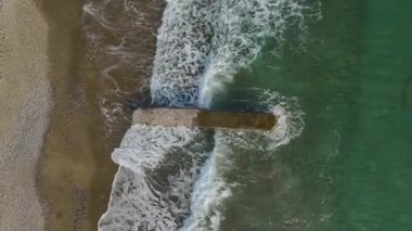 Huzurlu bir taş iskelenin üzerinden uçun boş bir sahilde çarpıcı masmavi sularla, 4K 'da yakalanmış..