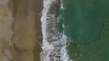 Bir taş iskele ve güzel gök mavisi suyla dolu boş bir plajın yer aldığı sakin bir sahil şeridini izleyin, 4K 'da çekilmiştir..