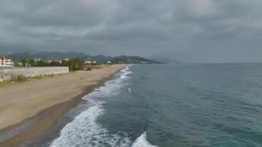 Boş bir kumsalda, sersemletici bir şekilde yakalanmış, mavi sularla dolu bir taş iskelenin huzurlu manzarasına bakın..