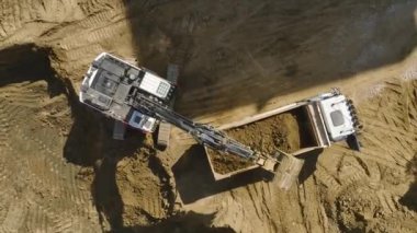 Yüksek çözünürlüklü 4K ile yakalanan, toprağı kamyonlara yükleyen kazıcı ile dolu şantiyeye bakın.