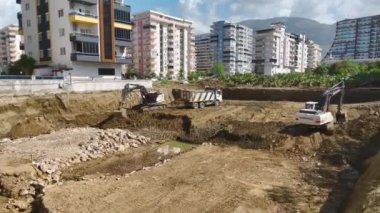 Yukarıdan 4K içinde kaydedilen toprağı kamyonlara yükleyen bir kazıcının ayrıntılı sürecine bakın.