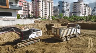 Kazıcının kamyonlara toprak yüklediği bir inşaat sahasının üzerinden uç, güzel 4K 'da yakalandı..