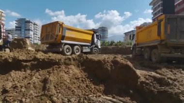 Bir inşaat sahasında yapılan operasyonları bir kazıcının kamyonlara toprak yüklediği, 4K 'da yakalanan bir kazıcıyla deneyin..