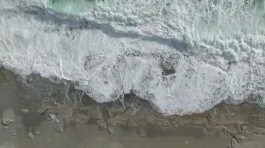 Akdeniz boyunca gök mavisi dalgaların 4K 'da yakalandığı dramatik fırtınalı kıyı şeridine bakın..