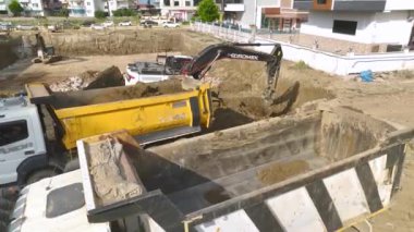 Kamyon ve kazıcılı bir inşaat sahasında vakıf hazırlığının 4K hava görüntülerini kaydet.