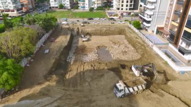 İnşaat alanındaki ağır makinelerin 4K drone görüntüsünü izleyin. Çalışkan ve güçlü bir sahne..