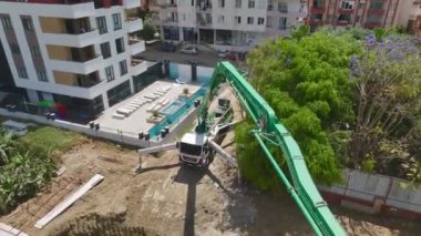 Aerial View 4K: Ağır makinelerin çukura beton dökerek yüksek bir binanın temelini oluşturduğu yukarıdan İzleme Kazısı 'na Ağır Makineler Dökülüyor.