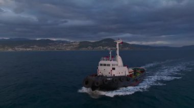 Gün batımında limana giden bir römorkör gibi limanın canlanmasını izleyin. Gökkuşağı ve şehir manzarası 4K 'da..