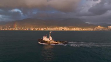 Gün batımında rıhtıma giden bir römorkörün rengarenk gökyüzü, şehir ve 4K 'da büyük bir gökkuşağı olduğuna tanık olun..