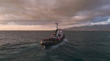 Gün batımında renkli bir römorkör yolculuğunun tadını çıkarın. Deniz ve şehir üzerinde parlak bir gökkuşağı, hepsi 4K hava manzaralı..