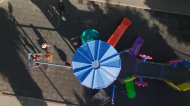 Çocukların kahkahalarının havayı doldurduğu renkli bir oyun parkının üzerinden uç, çarpıcı bir şekilde 4K.