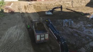 İnsansız hava aracı görüntülerinde bir kazıcının bir inşaat sahasında dünyayı hareket ettirmedeki ustalığını gösteriyor..
