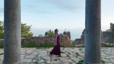 Gün batımında antik bir şehirde gezen bir prenses mankeni görün, hepsi 4K 'da yukarıdan izleniyor..