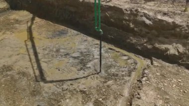 İnşaat alanında ağır ekipmanlar çukuru betonla doldururken temellerin oluşumuna bakın..