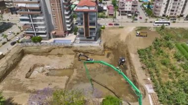 Ağır makineler çukura beton dökerken inşaatın başlangıcına tanık olun..