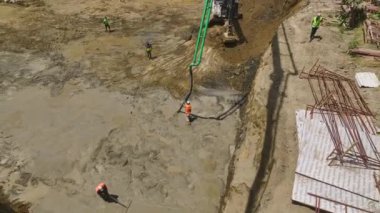 Ağır makinelerin kazılarını izleyin ve yukarıdan gelecek çok katlı bir binanın temelini oluşturmak için beton dökün..