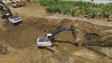 Makineler bir çukurda çalışırken, bir gökdelen temeli oluşturmak için beton dökerken hareketi gözlemleyin..