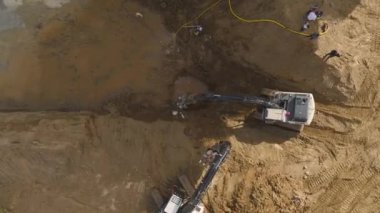 İnşaat alanında makineler ve insanlar birlikte çalışıyorlar..