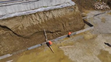 İşçiler bina temellerini oluştururken metal topluluğunu gözlemleyin.