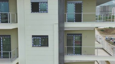Dış görünüş çalışmalarını tamamlayan ve yeni evlere hava perspektifinden pencere takan işçiler.