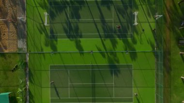 Boş yeşil bir tenis kortunun üzerinden uç, yukarıdan yakalanan yemyeşil ağaçların arasına saklan..