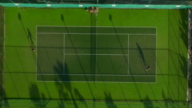 Açık gökyüzünün altında boş bir tenis kortunun sakinliğini hisset..