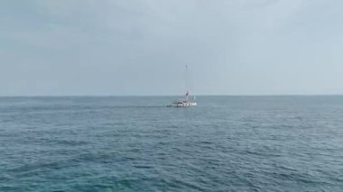 İndirilmiş yelkenli bir yatın güzel Akdeniz kıyı şeridinde süzülüşünü izleyin..
