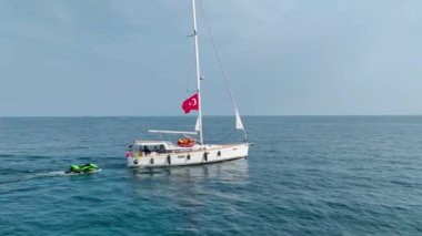 Akdeniz kıyılarında huzur içinde yüzen, yelkenleri açık bir yat görüyorum..