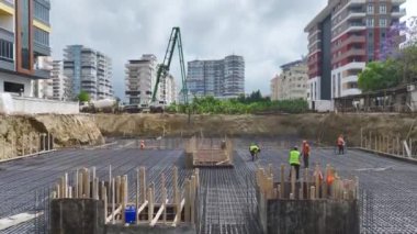 Beton döken ve temeli metal çubuklarla güçlendiren işçiler.