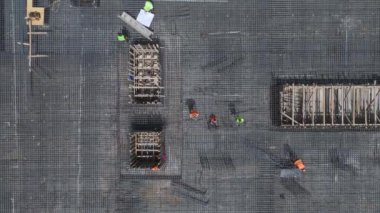 İşçilerin beton döküp metal parmaklıkları güçlendirdiği işlek bir inşaat alanına bakın..