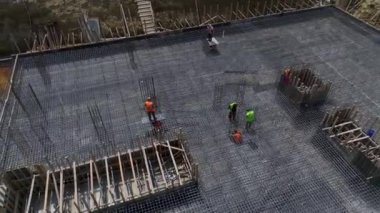 İnşaat işçilerinin inşaat sahasına beton döküp metal destekleri yerleştirdiklerini gözlemleyin