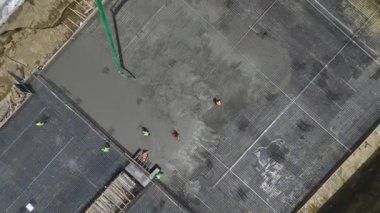 İnşaat alanını beton döken ve metal parçaları birleştiren işçilerle gözlemleyin.