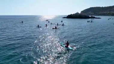 Akdeniz gölünün sakin sularında yaz güneşinin tadını çıkaran bir grup kürekçi görün..