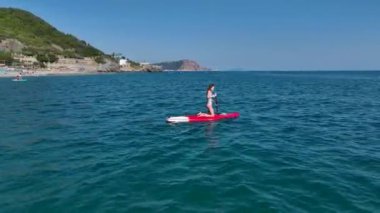 Sakin ve manzaralı bir körfezde SUP festivalinde eğlenen kürekçileri izleyin..