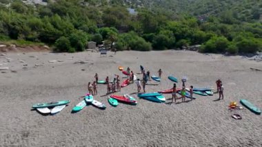 Güzel bir koyda yaz SUP festivali sırasında kürek çekenleri seyredin..