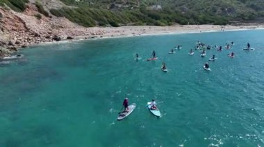 Yaz SUP festivali sırasında açık denizde kürek çeken ve eğlenen insanları izleyin..