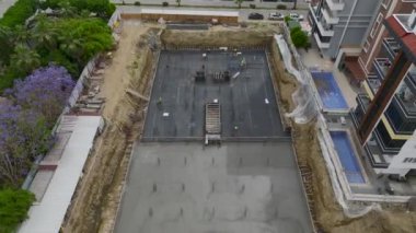 İşçiler temellerine beton dökerken çok katlı bir binanın büyük inşaatını izleyin..