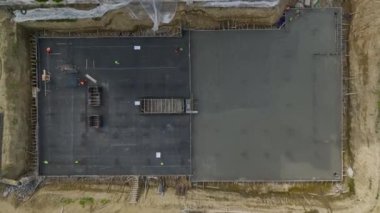 İşçiler büyük çok katlı bir binanın temellerine beton döküyorlar.