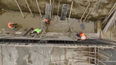 İşçilerin aktif olarak çalıştığı büyük bir inşaat sahasına kanalizasyon boruları kurma sürecini izleyin.
